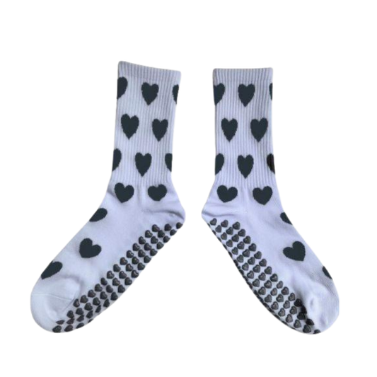 White socks with black heart patterns and textured sole on a white background