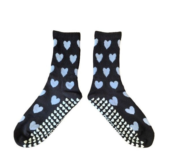 Black socks with blue heart patterns and white textured sole on a white background