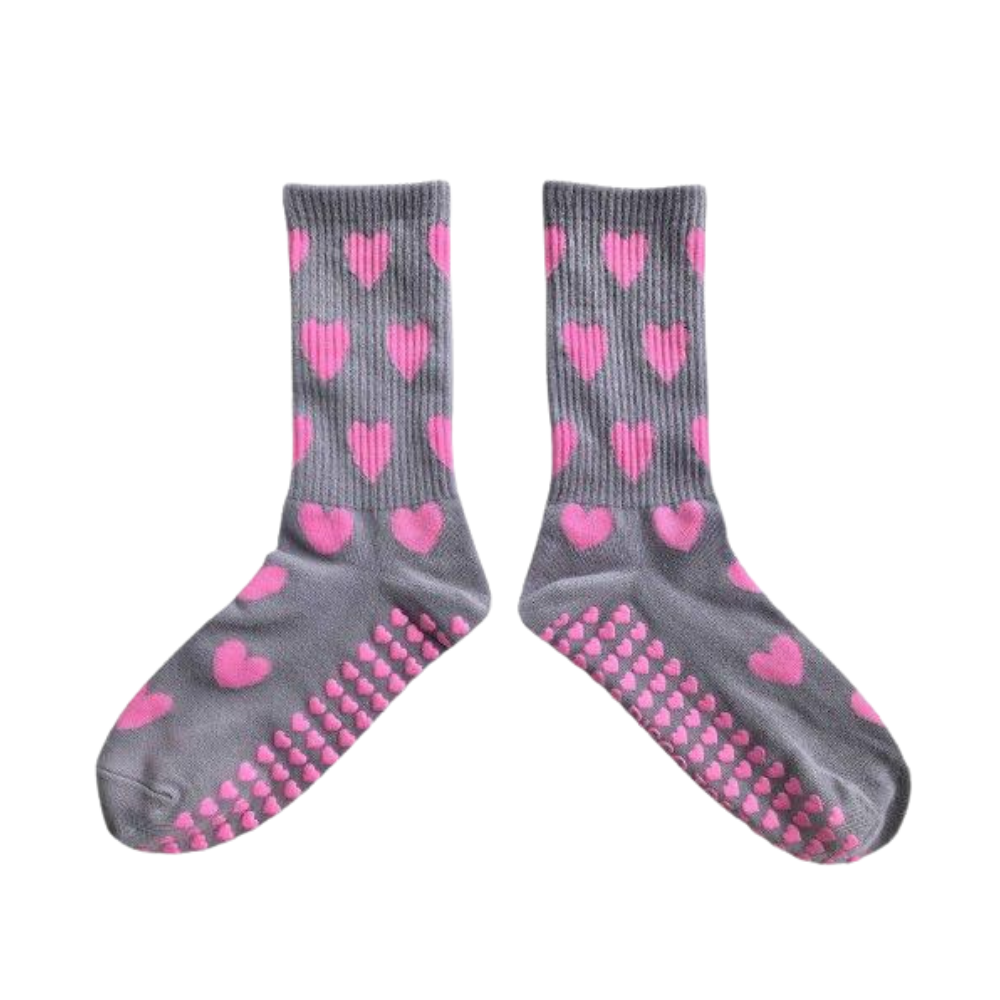 Gray socks with pink heart patterns and textured sole on a white background
