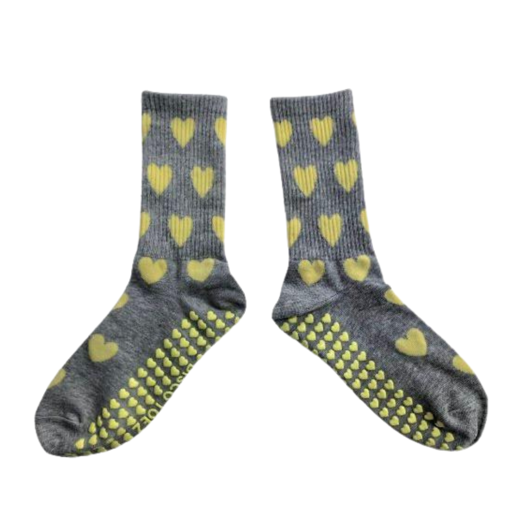Gray socks with yellow heart patterns and textured sole on a white background