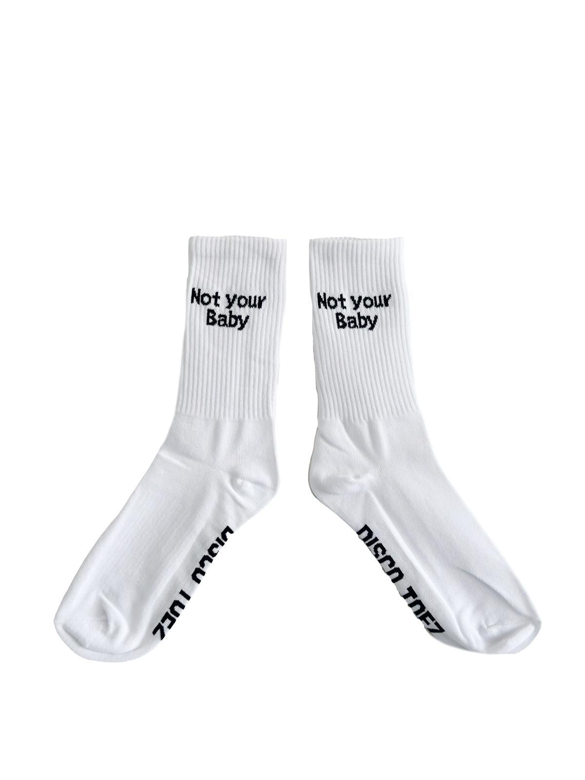 A pair of white socks with black text 'not your baby' on a white background