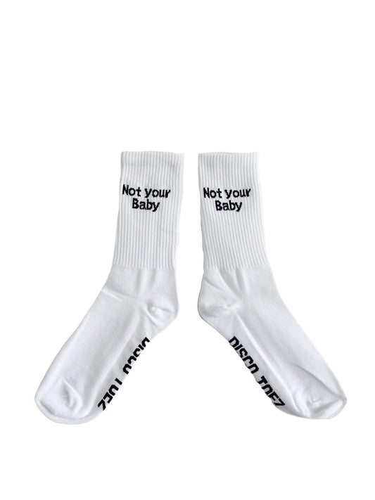 A pair of white socks with black text 'not your baby' on a white background